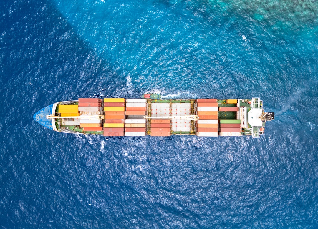 A top-down aerial view of a large container ship navigating through the ocean near Curacao